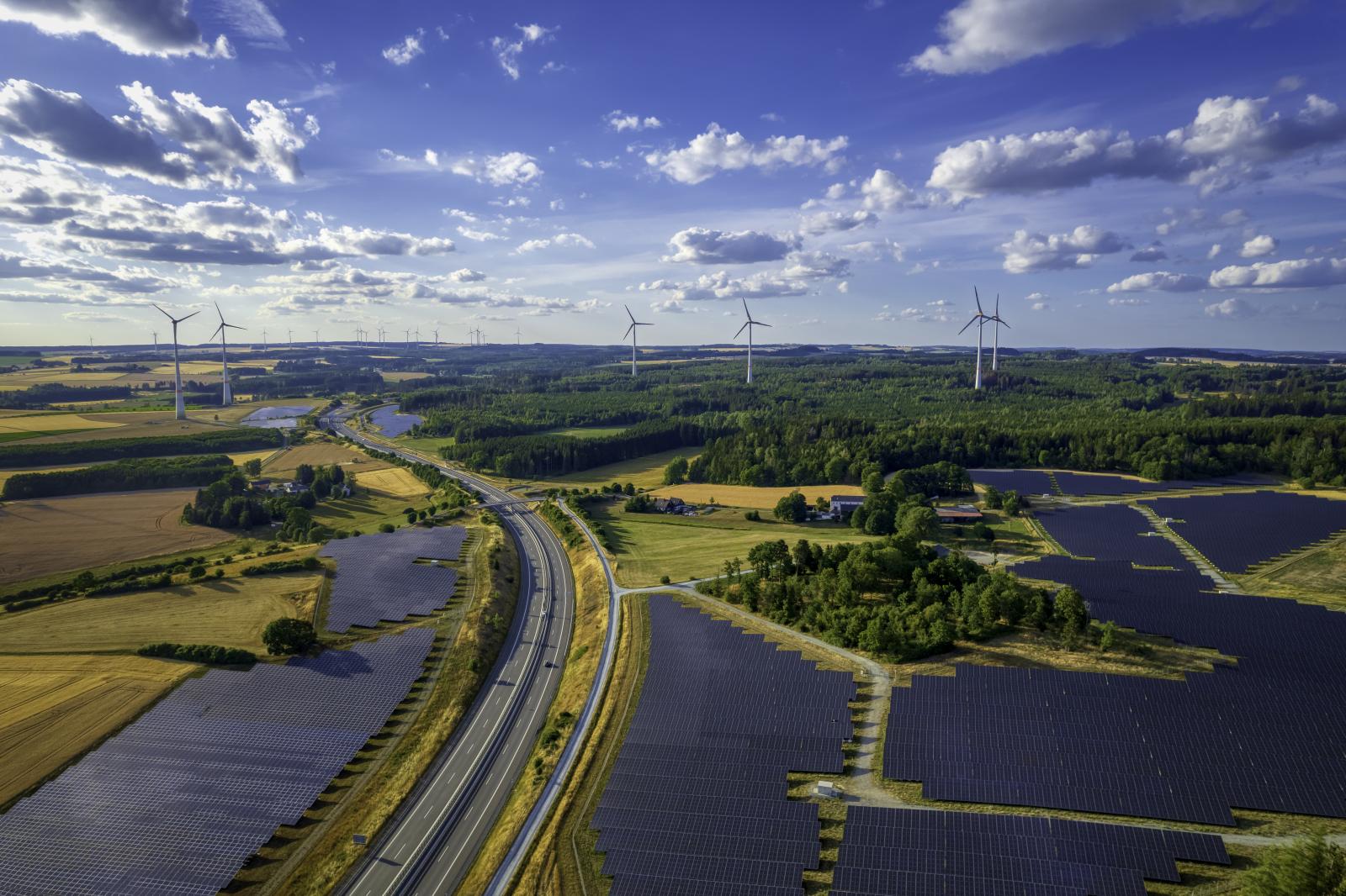 Solar farm and wind turbines near the highway road interchange (aerial)